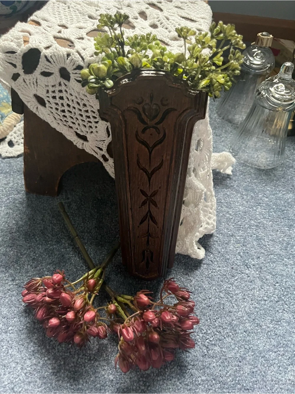 Carved Dark Wood Wall Pocket Vase will include a sprig of greenery
